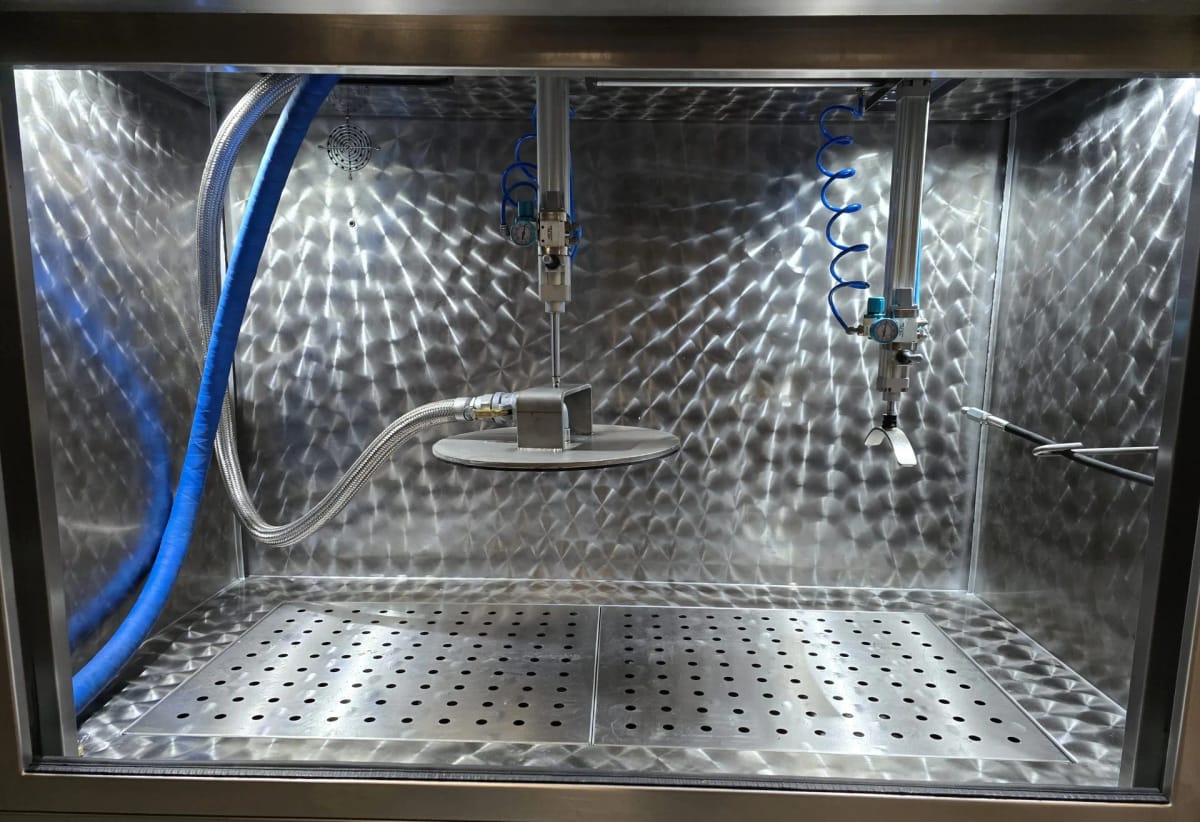 Inside an empty METClean XL chamber, with the wash hose, clamp arms and perforated floor