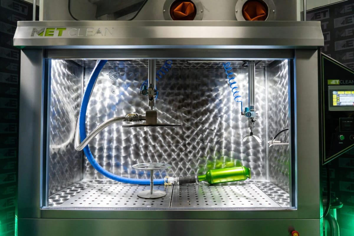 The lit chamber of a METClean XL with a component connected to the wash hose on the loading floor